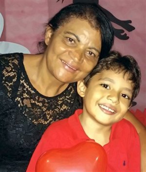 A Célia sorrindo abraçada com o João, já maior, os dois de bochecha colada